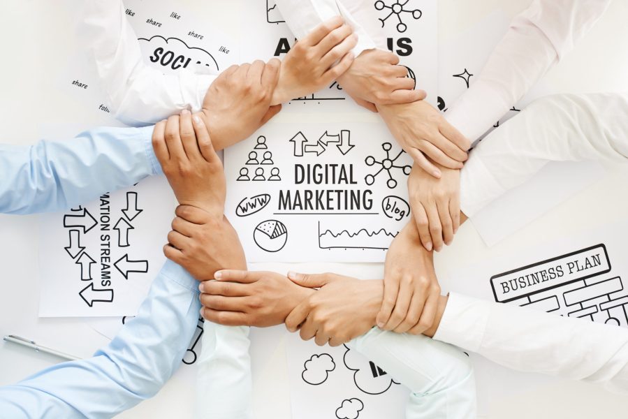 Business team making ring of hands above digital marketing drawing